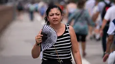 Seseorang menggunakan kipas tangan saat berjalan melintasi Jembatan Brooklyn, New York City, Senin (15/7/2024). (Adam Gray / GETTY IMAGES NORTH AMERICA / Getty Images via AFP)