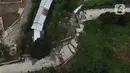 Foto udara kondisi jalan yang terbelah akibat pergeseran tanah di kawasan Bojong Koneng, Babakan Madang, Kabupaten Bogor, Jawa Barat, Jumat (16/9/2022). Badan Penanggulangan Bencana Daerah (BPBD) setempat mencatat 18 unit rumah mengalami kerusakan, dan pergeseran tanah itu menyebabkan retakan-retakan di tanah, dinding, plafon dan lantai rumah warga serta akses jalan sudah tidak bisa dilewati oleh kendaraan roda dua dan roda empat. (Liputan6.com/Herman Zakharia)