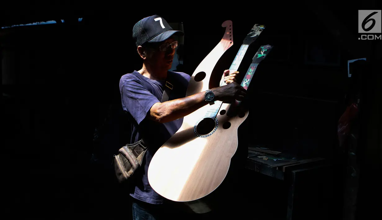 I Wayan Tuges melihat gitar yang telah diukirnya di workshop pembuatan gitar berlabel Blueberry di Jalan Baruna No. 5 Guwang, Sukowati, Bali, Senin (15/10). Gitar tersebut banyak dipesan oleh musisi lokal hingga mancanegara. (Liputan6.com/Angga Yuniar)