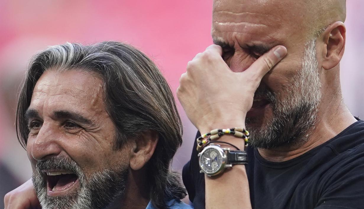 Pelatih Manchester City, Pep Guardiola (kanan), menyeka air matanya setelah berhasil membawa timnya keluar sebagai juara Piala FA 2022/2023 dalam pertandingan final FA Cup melawan Manchester United yang berlangsung di Wembley, Sabtu (3/6/2023) WIB. (AP Photo/Dave Thompson)