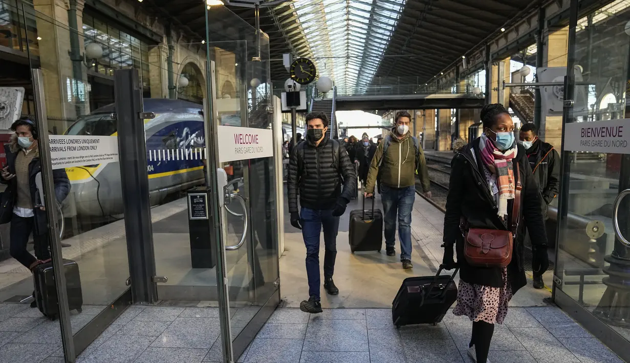 Penumpang yang tiba dari London dengan kereta Eurostar, mengenakan masker untuk melindungi dari COVID-19 keluar dari gerbang kedatangan di stasiun kereta Gare du Nord, Paris, Jumat (14/1/2022). Prancis telah mencabutnya Larangan COVID terhadap turis Inggris mulai (14/1). (AP Photo/Michel Euler)