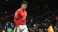 Striker Manchester United, Alexis Sanchez tertunduk sambil berjalan usai kalah dari Sevilla pada leg kedua 16 besar Liga Champions di Old Trafford, Selasa (13/3). Hasil ini membuat langkah Manchester United di Liga Champions terhenti. (Oli SCARFF/AFP)