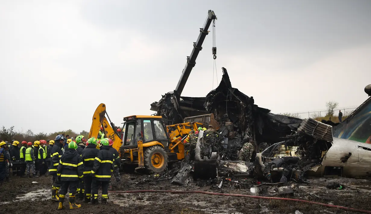 Tim penyelamat berusaha mengangkat puing pesawat yang jatuh di dekat Bandara Internasional Kathmandu, Nepal, Senin (12/3). Pesawat yang kecelakaan merupakan maskapai US-Bangla Airlines. (Prakash MATHEMA/AFP)