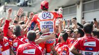 Gaya Andrea Dovizioso (tengah) merayakan kemenangan bersama tim usai balapan MotoGP Austria di Red Bull Ring, Spielberg, Austria (13/8/2017). Dovizioso menjadi juara stelah kalahkan Marquez pada lap terakhir. (AFP/Jure Makovec)