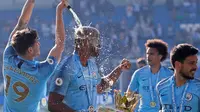 Pemain Manchester City John Stones menuangkan sampanye pada rekan setimnya Vincent Kompany yang memegang trofi Liga Inggris usai mengalahkan Brighton di Stadion AMEX, Brighton, Inggris, Minggu (12/5). (AP Photo/Frank Augstein)