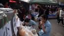 Dua wanita menikmati makan siang di pasar di Beijing (20/11). (AFP Photo/Nicolas Asfouri)