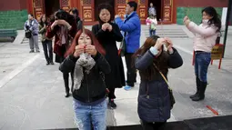 Zheng Liping (kiri depan) bersama warga lainnya berdoa untuk suaminya, Ju Kun yang hilang pada tahun 2014 di Kuil Lama di Beijing, Cina,(8/3). Pesawat Malaysian Airlines MH370 telah hilang selama dua tahun. (REUTERS/Kim Kyung-hoon)