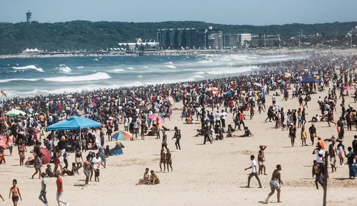 Ribuan wisatawan bersuka ria saat perayaan Tahun Baru di South Beach, Durban, Afrika Selatan, 1 Januari 2022. Pemerintah Afrika Selatan mencabut pembatasan COVID-19 dengan menghapus jam malam dari tengah malam hingga pukul 04.00. (Rajesh JANTILAL/AFP)