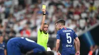 Wasit wanita Stephanie Frappart memberikan kartu kuning kepada pemain Chelsea, di laga UEFA Super Cup: Liverpool vs Chelsea, Rabu (14/8). (Bulent Kilic / AFP)