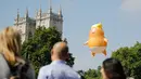 Balon raksasa berbentuk bayi menyerupai Presiden AS, Donald Trump melayang dekat menara Westminster Abbey selama demonstrasi di Parliament Square, London, Jumat (13/7). Puluhan ribu orang menggelar aksi damai menentang kedatangan Trump. (AFP/TolgaAKMEN)