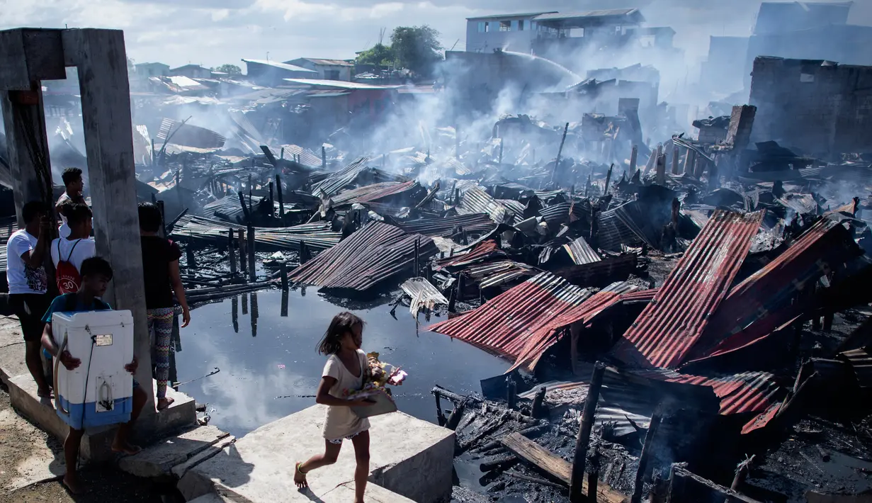 Sejumlah warga melihat rumah-rumah mereka hangus terbakar di sebuah daerah kumuh di Navotas, Manila (8/11). Dilaporkan sekitar 150 keluarga terkena dampak kebakaran tersebut. (AFP Photo/Noel Celis)