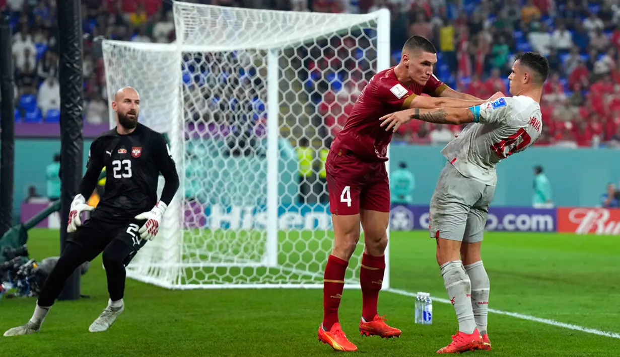 Pemain Serbia Nikola Milenkovic (tengah) mendorong pemain Swiss Granit Xhaka pada pertandingan sepak bola Grup G Piala Dunia 2022 di Doha, Qatar, 2 Desember 2022. Swiss melaju ke babak 16 besar Piala Dunia 2022 setelah mengalahkan Serbia dengan skor 3-2. (AP Photo/Ricardo Mazalan)