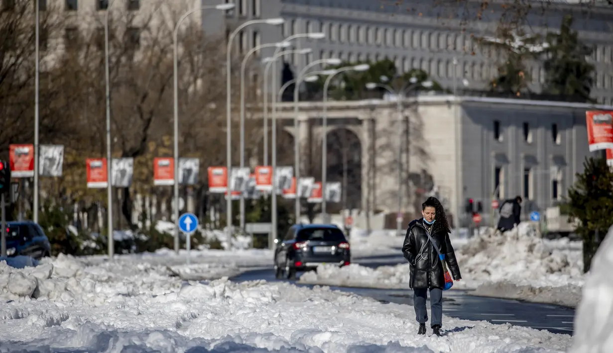 Seorang wanita berjalan di sepanjang Paseo Castellana yang tertutup salju di Madrid, Senin (11/1/2021). Ibu kota Spanyol itu berusaha bangkit kembali setelah menghadapi badai salju terburuk dalam 50 tahun terakhir yang melumpuhkan sebagian besar wilayah Spanyol tengah. (AP Photo/Manu Fernandez)