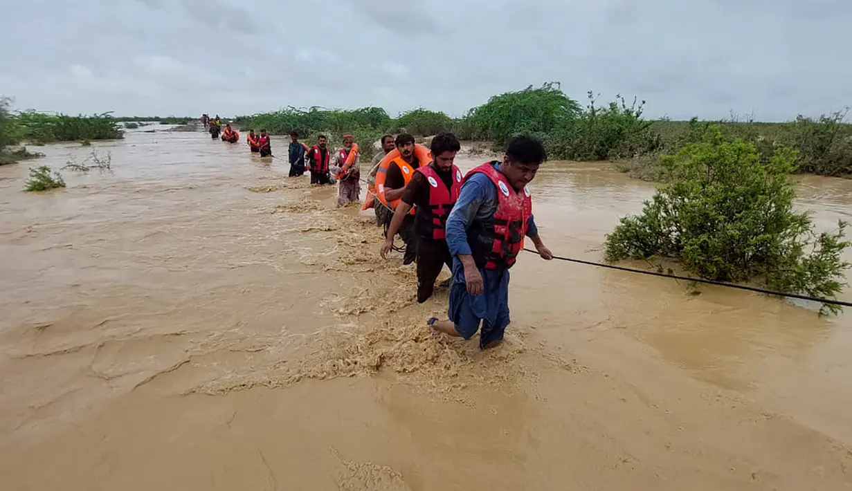 Petugas penyelamat membantu penduduk desa untuk mengevakuasi mereka dari daerah banjir yang disebabkan hujan lebat, di Lasbella, sebuah distrik di provinsi Baluchistan barat daya Pakistan (26/7/2022). Para pejabat mengatakan, pada hari Rabu, penyelamat yang didukung oleh pasukan menggunakan perahu dan helikopter untuk mengungsi ratusan orang terdampar dari barat daya Pakistan, di mana banjir yang dipicu oleh hujan telah menewaskan 104 orang sejak bulan lalu. (AP Photo/Hamdan Khan)