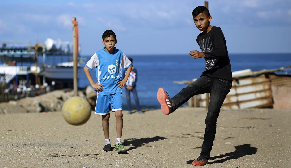 Seorang anak menendang bola saat bermain di kawasan Gaza, Jumat (3/11/2017). Sepak bola tidak hanya menjadi olahraga favorit, tapi juga sebagai salah satu cara bagi warga untuk mengurangi ketegangan akibat peperangan. (AFP/Mohammed Abed)