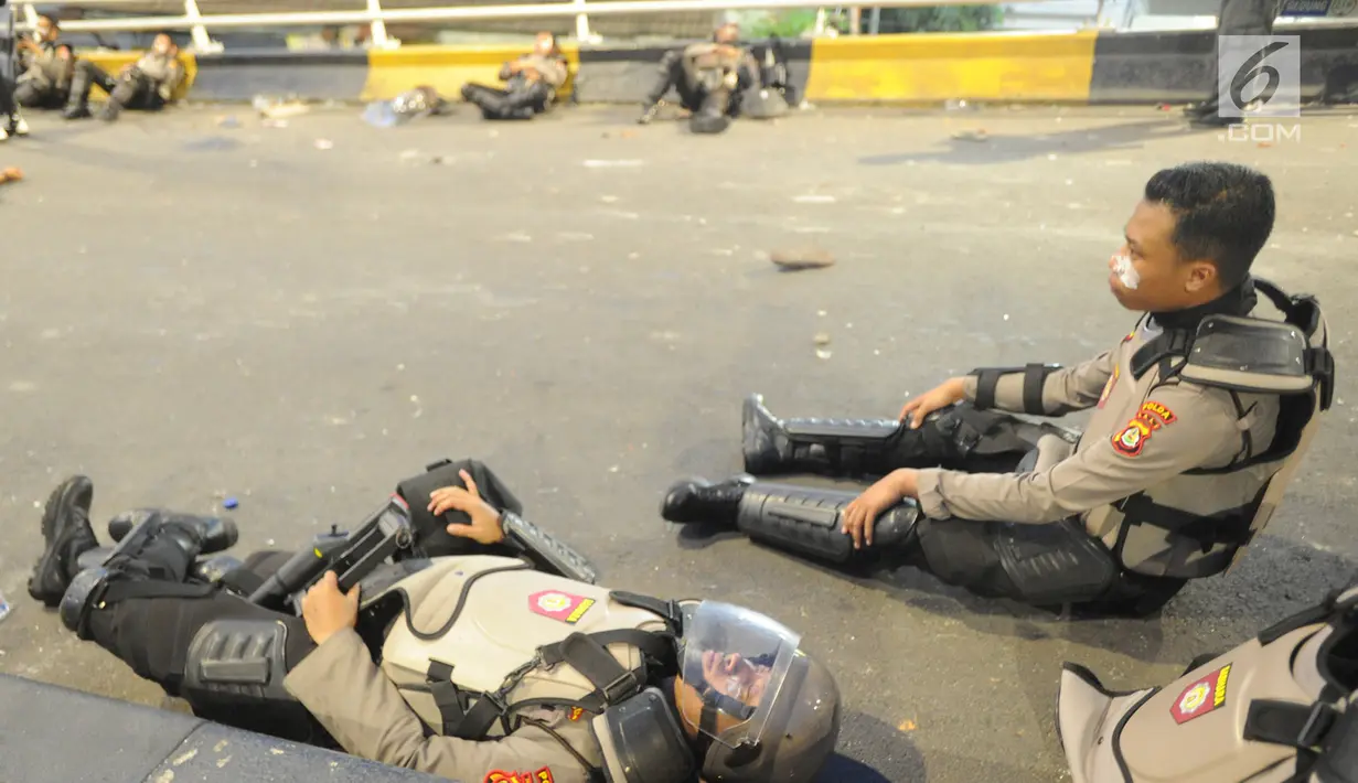 Anggota Dalmas BKO dari Polda Bali beristirahat usai mengamankan perusuh di atas fly over Slipi, Jakarta, Rabu (22/5/2019). Bentrokan panjang dengan para perusuh membuat anggota kepolisian yang berhadapan langsung kurang beristirahat. (merdeka.com/Arie Basuki)