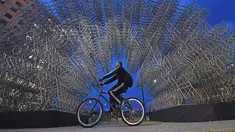 Seorang pria mengendarai sepeda melewati instalasi seni seniman China Ai Weiwei yang berjudul 'Forever Cycles' di Rio de Janeiro, Brasil, Senin (19/8/2019). Instalasi ini terdiri lebih dari 1.000 sepeda stainless steel. (CARL DE SOUZA/AFP)