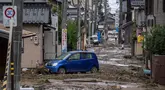 Sebuah mobil yang terdampar terlihat di jalan yang tertutup lumpur setelah hujan lebat di kota Wajima, prefektur Ishikawa, Jepang, pada tanggal 22 September 2024. (Yuichi YAMAZAKI/AFP)
