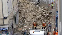 Petugas pemadam kebakaran berada dekat bangunan yang runtuh di Marseille, Prancis, Senin (5/11). Wali Kota Marseille Sabine Bernasconi meminta, seluruh warga untuk dipindahkan dari bangunan yang tengah dalam renovasi tersebut. (AP/Claude Paris)