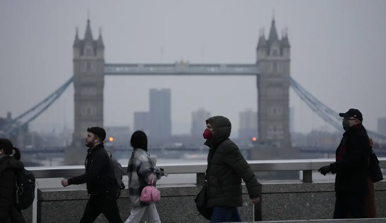 Pekerja berjalan di atas Jembatan London menuju distrik keuangan Kota London, dengan latar belakang Tower Bridge, pada jam sibuk pagi hari, Senin (24/1/2022). Inggris telah meminta orang-orang untuk kembali bekerja di kantor saat mereka melonggarkan pembatasan corona COVID-19. (AP Photo/Matt Dunham)