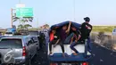 Pemudik memilih beristirahat di bak mobil terbuka saat terjebak macet di Tol Pejagan, Jawa Tengah, Senin (4/7). Akibat di tutupnya pintu keluar Tol Pejagan menyebabkan Tol Kalipanci-Pejagan macet. (Liputan6.com/Angga Yuniar)