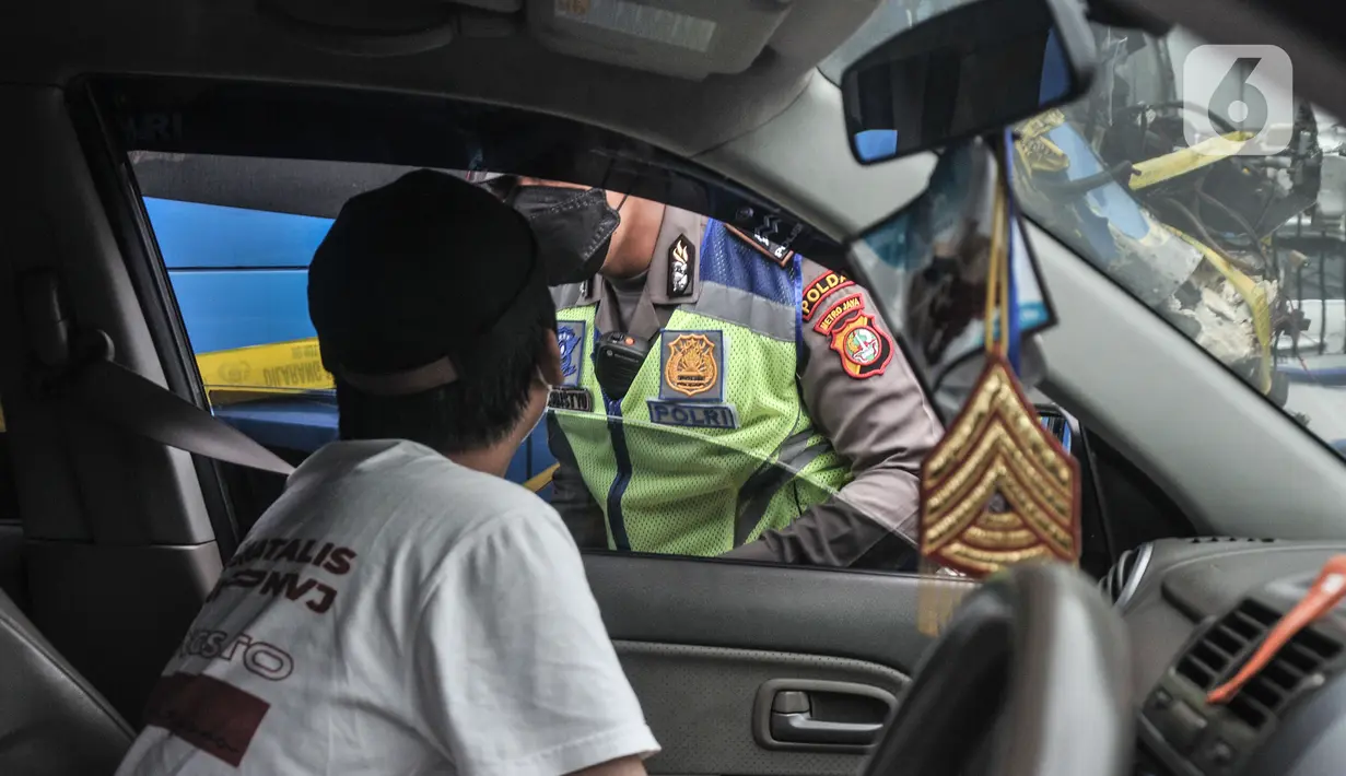 Petugas kepolisian menilang pengendara mobil yang melanggar aturan ganjil genap di Jalan MT Haryono, Jakarta, Kamis (28/10/2021). Direktorat Lalu Lintas Polda Metro Jaya mulai hari ini memberlakukan sanksi tilang kepada pelanggar ganjil genap di 13 ruas jalan DKI Jakarta. (merdeka.com/Iqbal S Nugroh