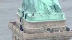 Petugas kepolisian membujuk seorang wanita yang memanjat Patung Liberty di New York, Rabu (4/7). Aksi wanita bernama Therese Okoumou ini memprotes kebijakan imigrasi pemerintah Presiden Donald Trump yang memisahkan keluarga migran. (AFP/PIX11 News/HO)
