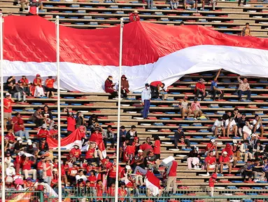 Pendukung Indonesia membentangkan bendera Merah Putih raksasa saat laga kedua Grup A Sepak Bola SEA Games 2023 antara Timnas Indonesia melawan Timnas Myanmar di Olympic Stadium, Phnom Penh, Kamboja, Kamis (04/05/2023). Skuad asuhan Indra Sjafri tersebut berhasil menang dengan skor telak 5-0. (Bola.com/Abdul Aziz)