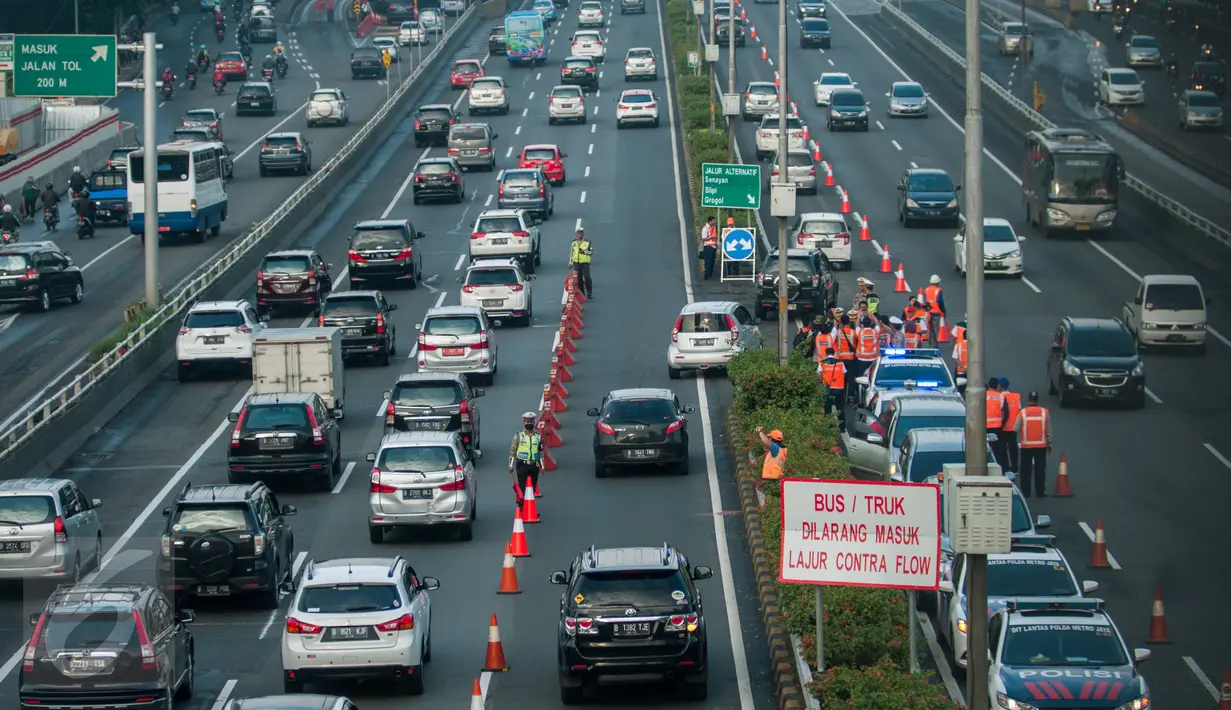 Petugas polisi dan Jasa Marga mengatur kendaraan yang melintasi sistem lawan arus (contraflow) di ruas tol dalam kota Cawang - Semanggi, Jakarta, Senin (13/2). Uji coba contraflow itu dilakukan dari Km 1+700 hingga Km 8+100. (Liputan6.com/Gempur M Surya)