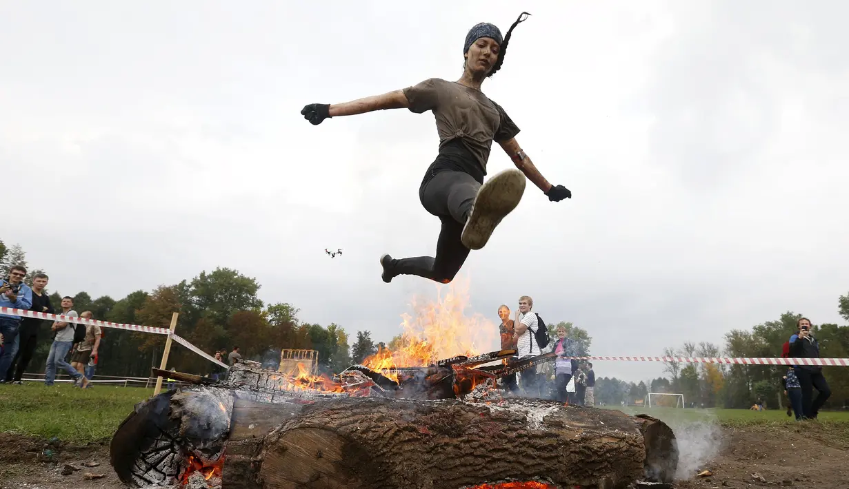 Seorang wanita melompat di atas api saat mengikuti kompetisi lari ekstrim di Zhodino, Minsk timur, Belarus, 26 September 2015. (REUTERS/Vasily Fedosenko)
