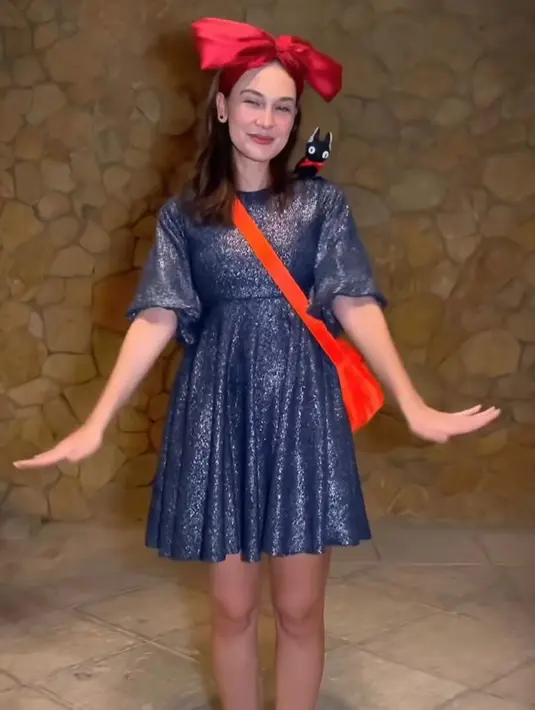 Luna Maya tampil manis dengan dress biru dan bandana pita merah khas tokoh Kiki Delivery Service. [Instagram/lunamaya]