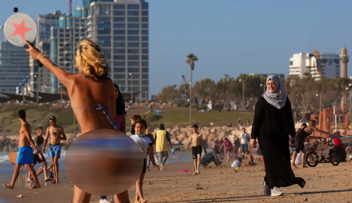 Warga Palestina dan Israel menikmati laut Mediterania selama liburan Idul Fitri, di Tel Aviv, Israel (25/5/2020).  Idul Fitri menandai akhir bulan suci Ramadhan, perayaan tiga hari yang biasanya menggembirakan telah berkurang secara signifikan karena pandemi coronavirus. (AP Photo/Oded Balilty)