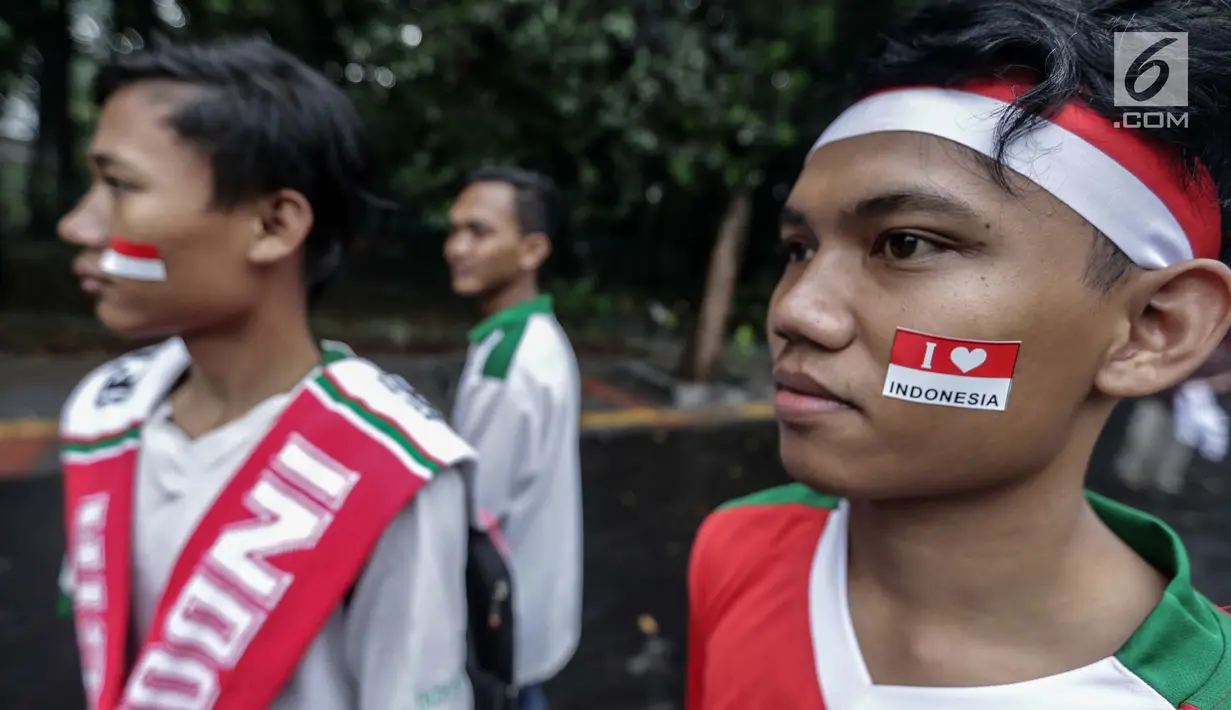 Suporter memakai atribut Timnas Indonesia jelang pertandingan kontra Islandia di Stadion GBK, Senayan, Jakarta, Minggu (14/1). Pelatih Timnas Indonesia, Luis Milla, menyiapkan kekuatan penuh untuk meladeni perlawanan Islandia. (Liputan6/Faizal Fanani)