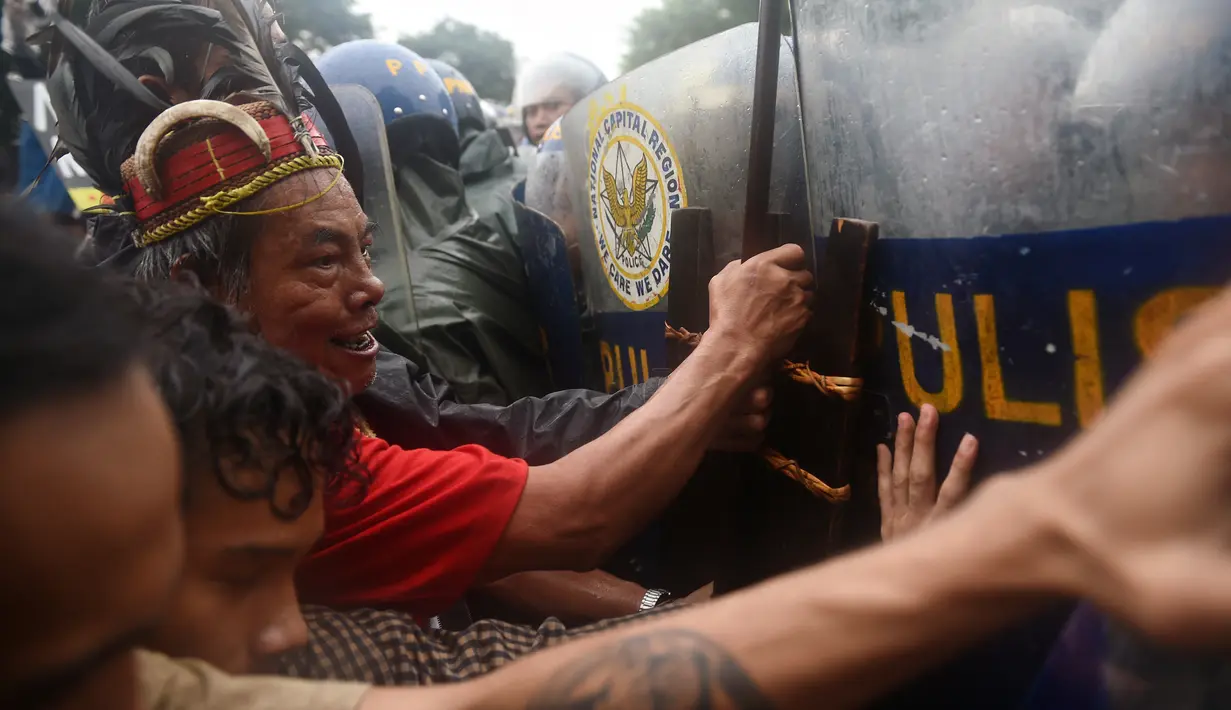 Demonstran terlibat saling dorong dengan polisi anti huru hara saat menggelar aksi pada ulang tahun Ferdinand Marcos ke-100 di Manila (11/9). Para demonstran menyerukan keadilan bagi korban darurat militer pada masa Ferdinand Marcos.(AFP Photo/Ted Aljibe)