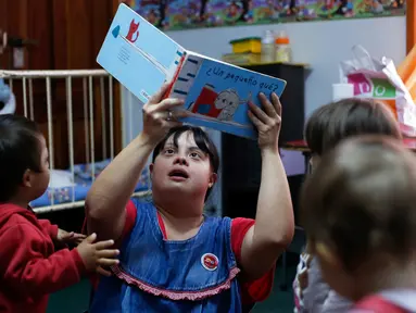 Seorang guru TK, Noelia Garella membacakan buku ke anak-anak saat bertugas di TK Jeromito, Cordoba, Argentina (24/10). Noelia 31 tahun merupakan penderita down syndrome pertama yang menjadi guru TK. (AFP Photo/Diego Lima)