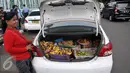 Seorang ibu berjualan di sela-sela Demo di depan Gedung DPR/MPR, Jakarta, Selasa (22/3/2016). Selain melakukan demo, supir taksi tersebut melakukan sweeping ke supir taksi yang beroperasi di dalam tol, dan membakar ban. (Liputan6.com/Johan Tallo)