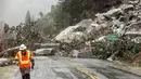 Petugas berjalan di dekat tanah longsor yang menutupi Highway 70 di zona Dixie Fire di Plumas County, California, Minggu (24/10/2021). Badai kuat menerjang California Utara yang sempat mengalami kebakaran hutan, memicu tanah longsor dan banjir, juga membawa angin kencang. (AP Photo/Noah Berger)