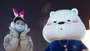 Seorang wanita memberi isyarat di Harbin Ice-Snow World di Harbin di Provinsi Heilongjiang, China timur laut, Sabtu (25/12/2021). Dunia Es-Salju Harbin ke-23 dibuka untuk umum pada hari Sabtu. (Wang Jianwei/Xinhua via AP)