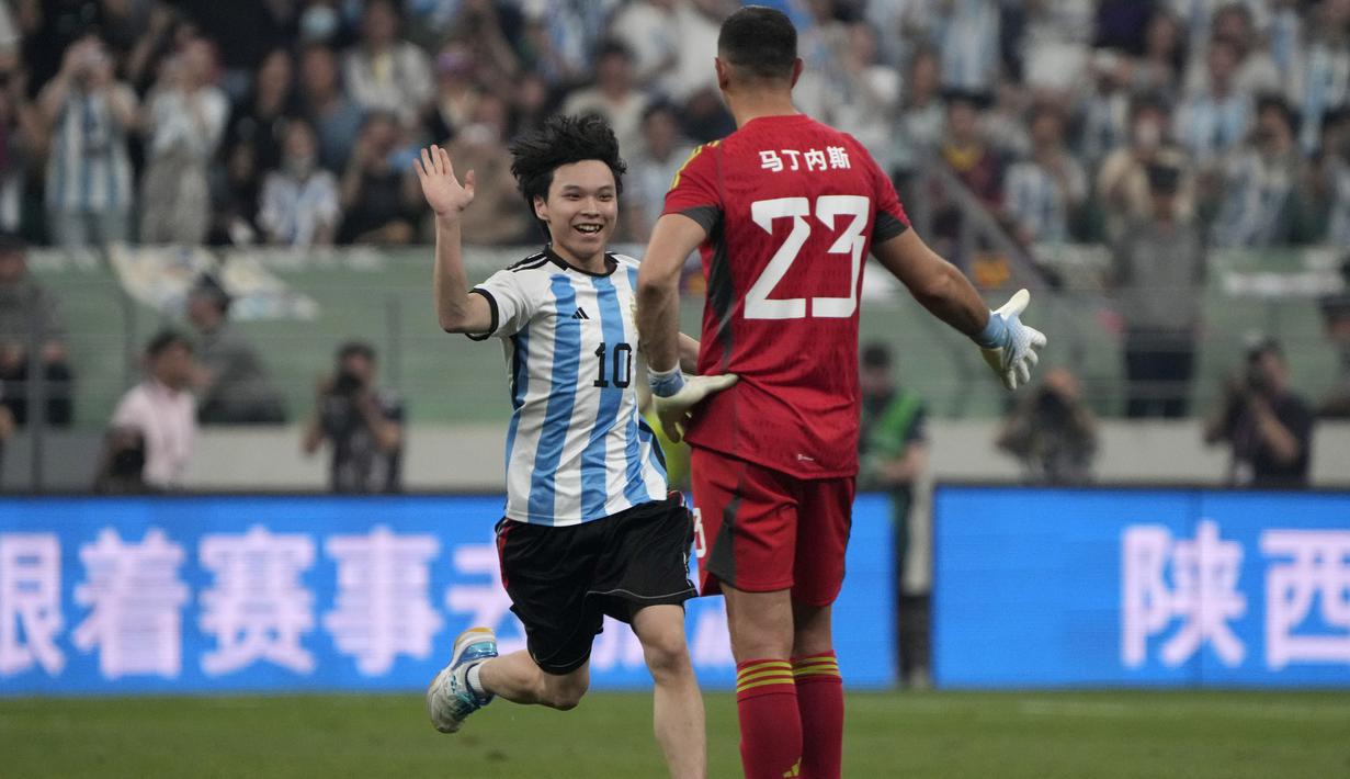 Seorang penyusup lapangan berlari mengajak tos kiper Argentina, Emiliano Martinez pada laga persahabatan antara Argentina melawan Australia di Workers' Stadium, Beijing, Kamis (15/06/2023). (AP Photo/Mark Schiefelbein)