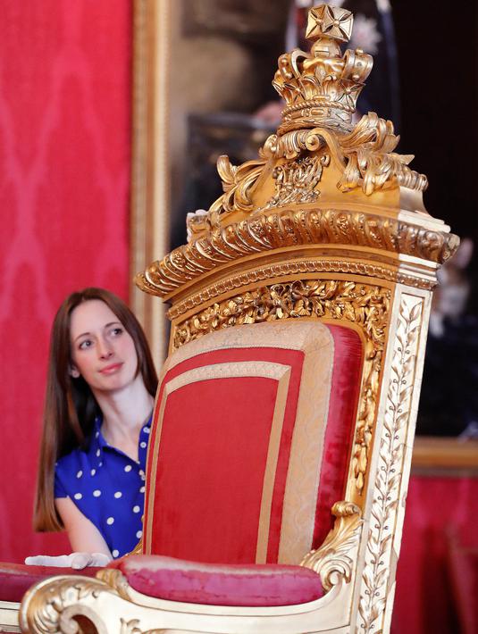 Pekerja berpose dengan singgasana milik Ratu Victoria sebagai bagian dari pameran di Istana Buckingham, London, Rabu (17/7/2019). Pameran yang dibuka pada 20 Juli tersebut menandai peringatan 200 tahun kelahiran Ratu Victoria. (AP Photo/Frank Augstein)