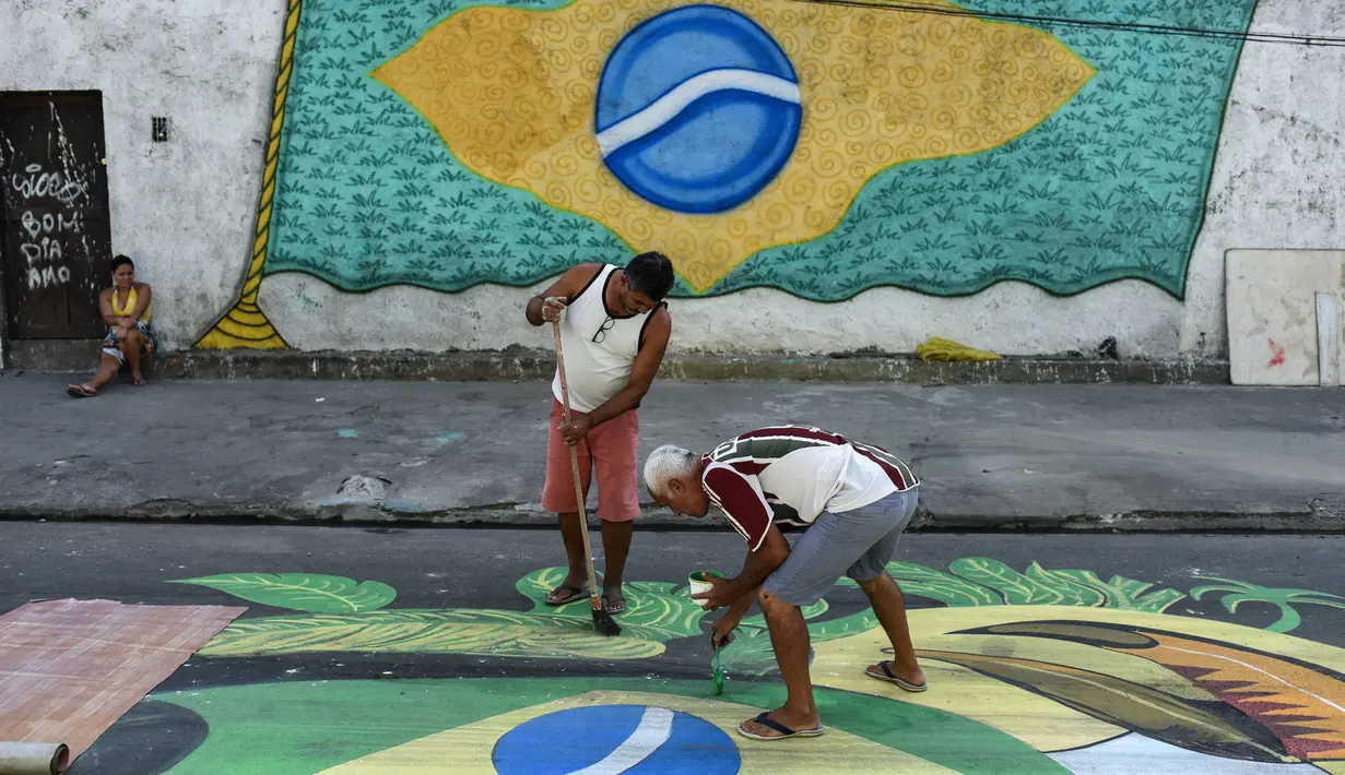 Pemandangan saat warga melukis mural Piala Dunia 2018 bergambar bendera Brasil di jalanan Camboata, Rio de Janeiro, Brasil, Kamis (31/6). (Fabio TEIXEIRA/AFP)