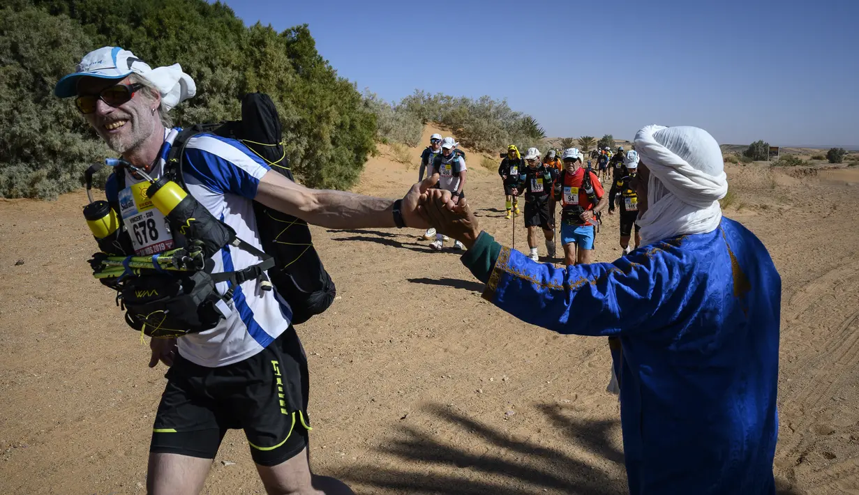 Warga menyemangati peserta lomba lari Marathon des Sables ke-34 tahap kedua di Gurun Sahara, Maroko, Senin (8/4). Marathon des Sables ke-34 diikuti hampir seribu peserta dari 50 negara. (JEAN-PHILIPPE KSIAZEK/AFP)