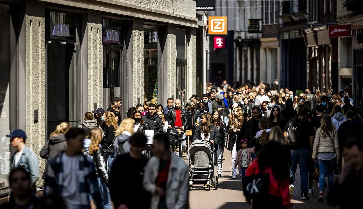 Pelanggan berjalan di Kalverstraat shopping street saat toko-toko diizinkan menerima pelanggan tanpa membuat janji di Amsterdam, Rabu (28/4/2021). Belanda melonggarkan pembatasan ketat terkait Covid-19, mengakhiri jam malam dan mengizinkan kafe untuk buka di luar ruangan. (REMKO DE WAAL/ANP/AFP)