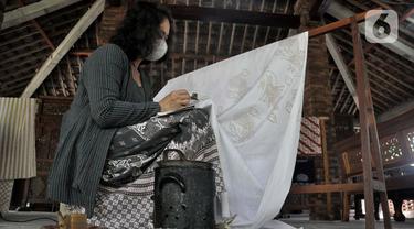 Rita saat menyelesaikan pembuatan batik tulis Lumbini di Dusun Tingal, Desa Wanurejo, Kecamatan Borobudur, Kabupaten Magelang, Jawa Tengah, Selasa (17/5/2022). Pasangan suami istri Adiwinarto (56) dan Rita (53) merintis batik tulis Lumbini pada 2011. (merdeka.com/Iqbal S. Nugroho)