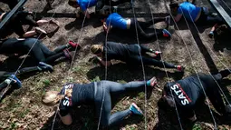 Sejumlah peserta merangkak dibawah kawat berduri saat mengikuti kompetisi Tough Viking di Stockholm, Swedia (12/5). Kompetisi ketangkasan ini dirancang oleh spesialis di Angkatan Bersenjata Swedia. (AFP/Jonathan Nackstrand)