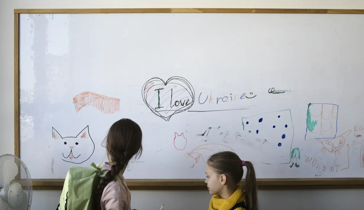 Dua anak pengungsi dari Ukraina berdiri di depan papan tulis sebelum kelas mereka dimulai di Berlin, Jerman, Senin, 21 Maret 2022. Empat puluh anak pengungsi Ukraina memulai hari pertama mereka di sekolah dasar di Berlin pada Senin hanya beberapa minggu setelah mereka melarikan diri dari perang pula