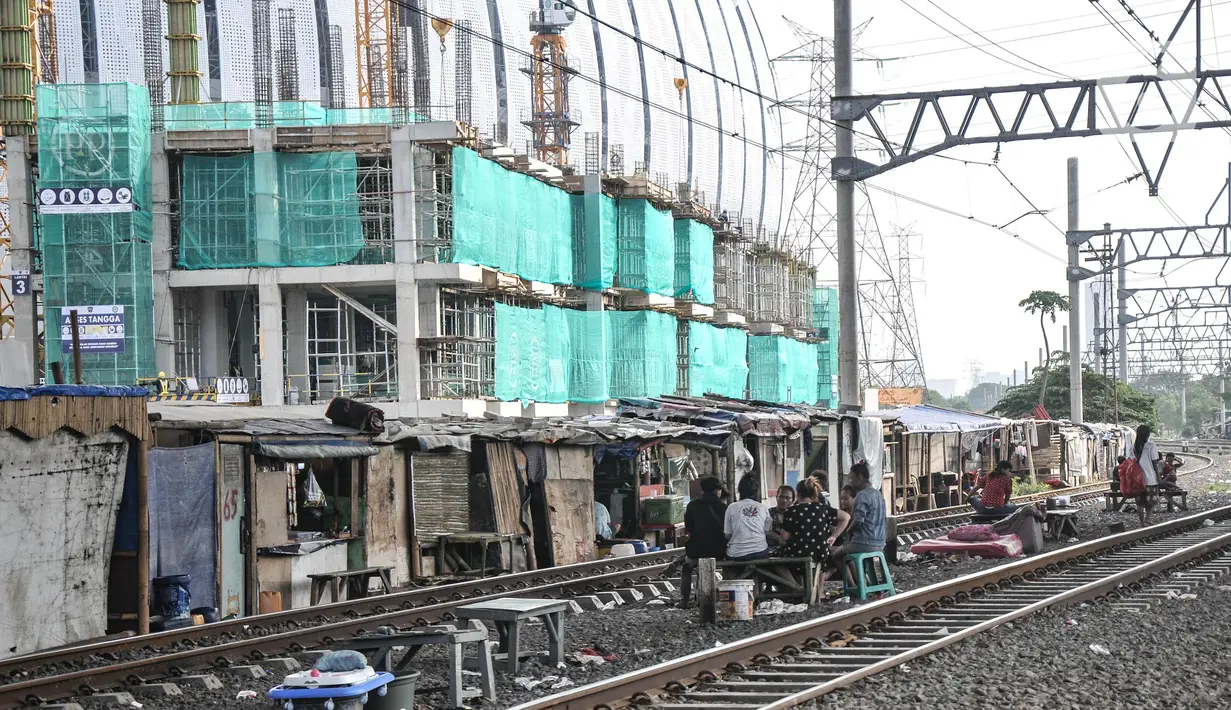 Aktivitas warga penghuni bantaran rel yang berada dekat dengan proyek pembangunan Kampung Susun Bayam, Papanggo, Tanjung Priok, Jakarta Utara, Selasa (12/7/2022). Kampung Susun Bayam rencananya memiliki empat lantai yang diperuntukkan bagi 138 keluarga dan ditargetkan rampung pada September 2022. (merdeka.com/Iqbal S. Nugroho)