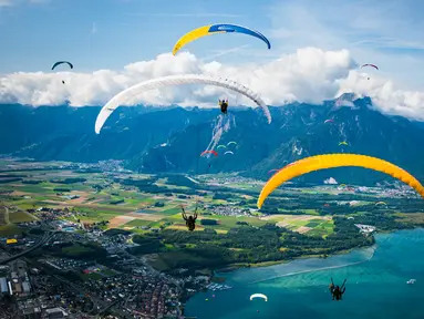 Puluhan paraglider melakukan penerbangan menuju pendaratan "Acro Show" di atas Danau Jenewa di Villeneuve, Swiss (20/8). Olahraga paragliding ini untuk tujuan rekreasi atau kompetisi. (Valentin Flauraud / Keystone via AP)