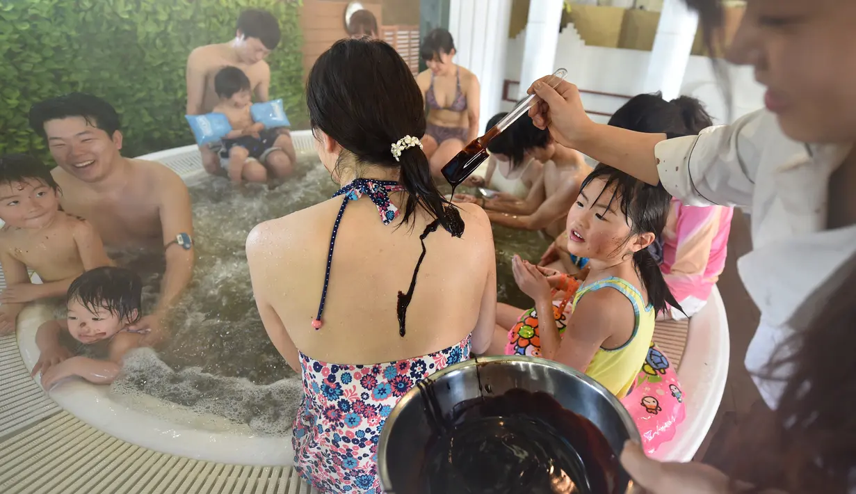 Petugas melumuri punggung pengunjung dengan cokelat cair saat mandi spa cokelat di Hakone, Jepang, Senin (13/2). Mandi spa cokelat diadakan dalam rangka menyambut Hari Valentine. (AFP PHOTO / Kazuhiro Nogi)