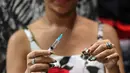 Jessica Nguyen mempersiapkan dosis suntik hormon di tokonya, Ho Chi Minh, Vietnam (30/3). Pemerintah Vietnam belakangan telah merancang UU mengenai hukum yang akan memungkinkan orang untuk secara resmi mengubah jenis kelamin. (AFP Photo/Hoang Dinh Nam)